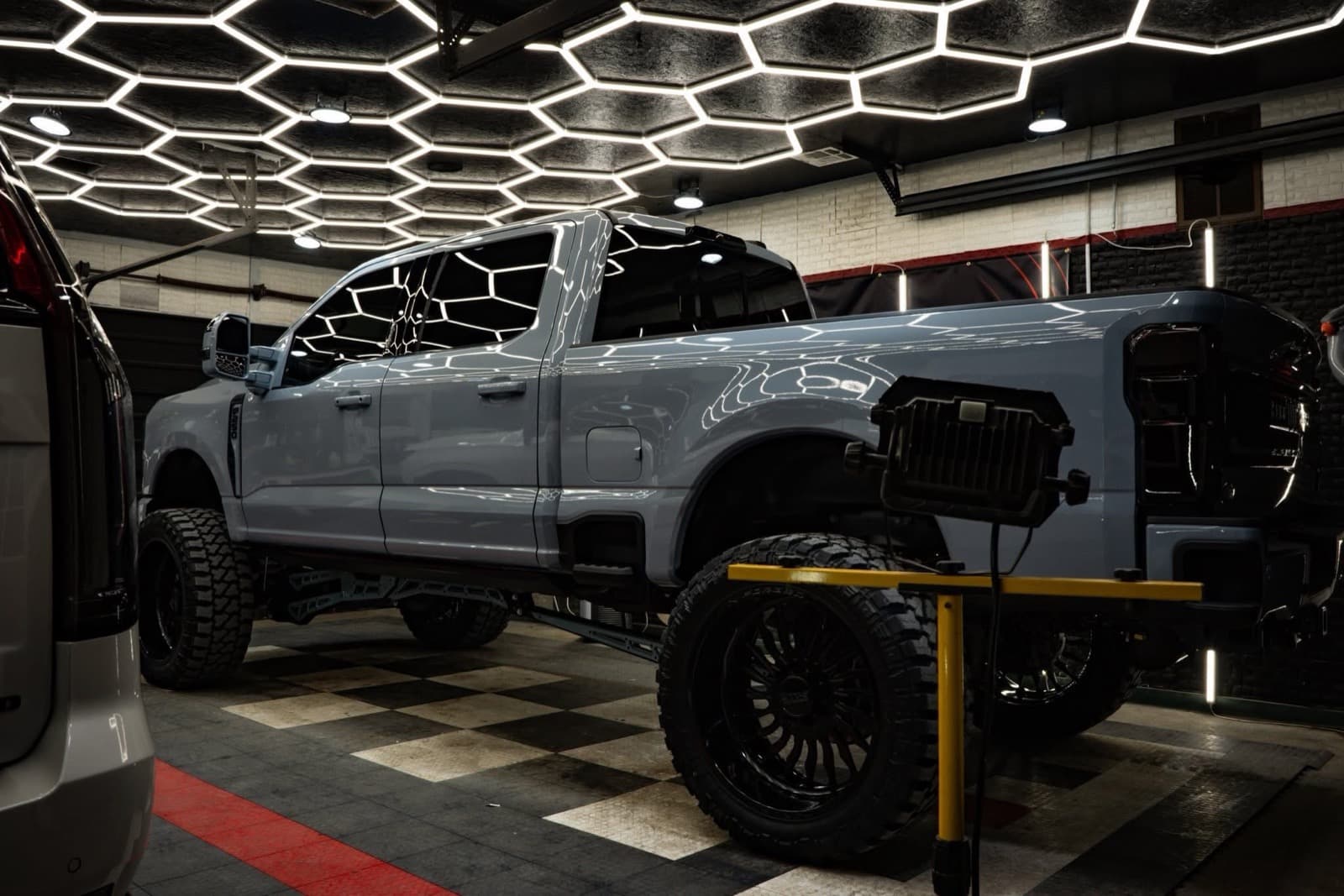 Lifted Ford F-250 Super Duty inside the hexagon-lit Elite Custom Automotive shop in Lockport, Louisiana — owned by Colin Richard